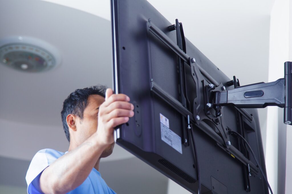 Profissional com ferramentas ajustando a instalação segura do suporte de Smart TV